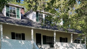 Une maison à deux étages avec un porche à l’avant, une cheminée en briques et le chiffre « 1903 » inscrit sur le mur.