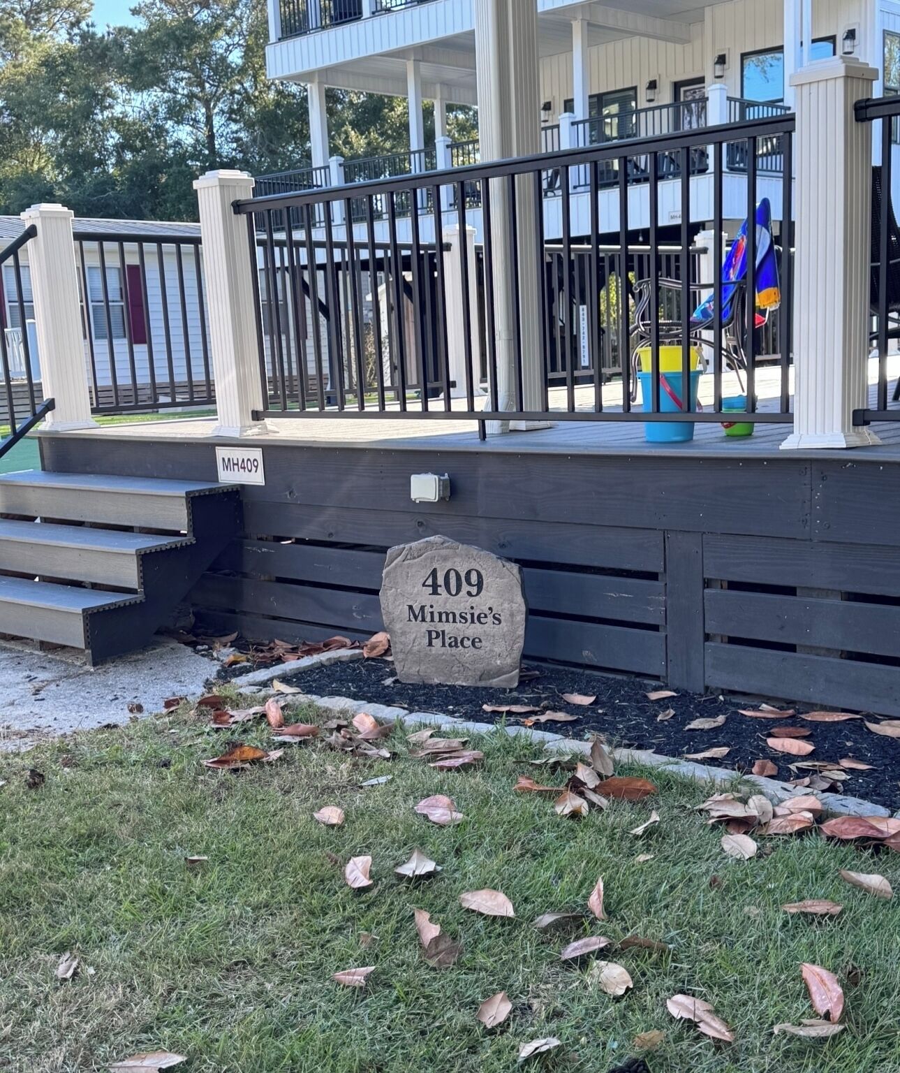 A stone sign with "409 Mimsie's Place" in front of a building with a porch and steps.