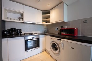 A compact kitchen with a stove, oven, microwave, and washing machine.