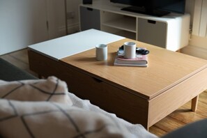 A neatly arranged bedroom with a bed, a bedside table with a book and a mug, and a wooden chest of drawers. - King Bed, Full Kitchen | Blackout Curtains (London)