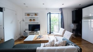 A modern living room with a sofa, coffee table, TV, and a balcony with a view.