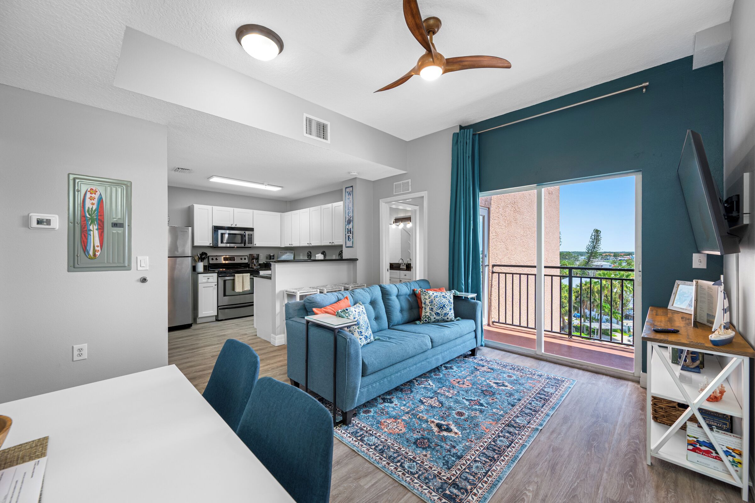 A modern apartment with a dining area, kitchen, and balcony.