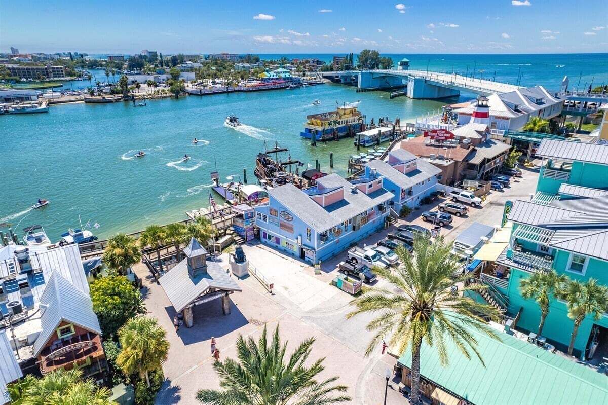 Un pueblo costero con puerto deportivo, barcos y un puente.
