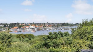 Un port de plaisance avec des bateaux, une ville en arrière-plan et de la verdure au premier plan.