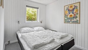 Une chambre à coucher avec un lit, une fenêtre et une œuvre d’art accrochée au mur.