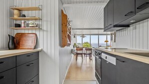 Une cuisine moderne avec des étagères en bois, un coin repas offrant une belle vue et une grande fenêtre.