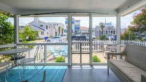 Un espacio exterior techado con una mesa de patio, sillas y un sofá de mimbre.