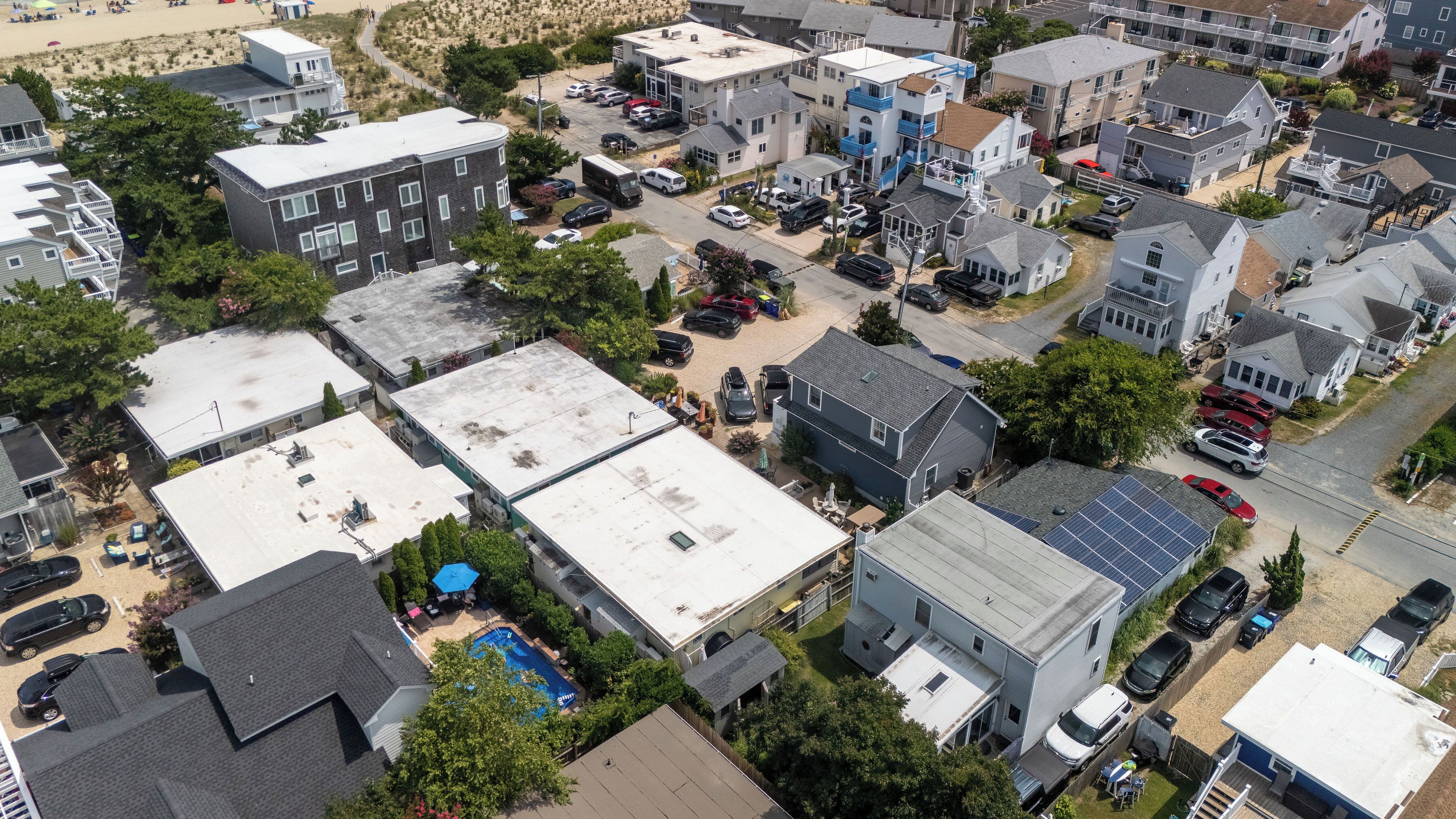 An aerial view of a residential area with multiple two-story houses, a swimming pool, and a parking lot.