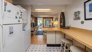 A compact kitchen with a refrigerator, a wooden counter, and a bar stool.