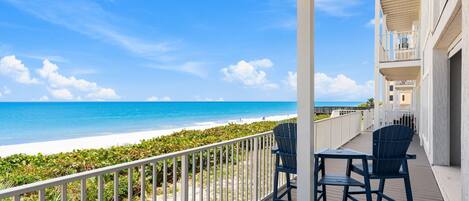 A balcony with a view of the beach and ocean.