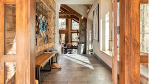 A wooden interior hallway with a stone floor, a bench, and a wall-mounted rack with skis. - Apex - Walk to Trails + Hot Tub | Sauna & Theater (Mountain Village)