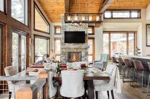 A spacious dining area with a stone fireplace, large windows, and a high ceiling. - Apex - Walk to Trails + Hot Tub | Sauna & Theater (Mountain Village)