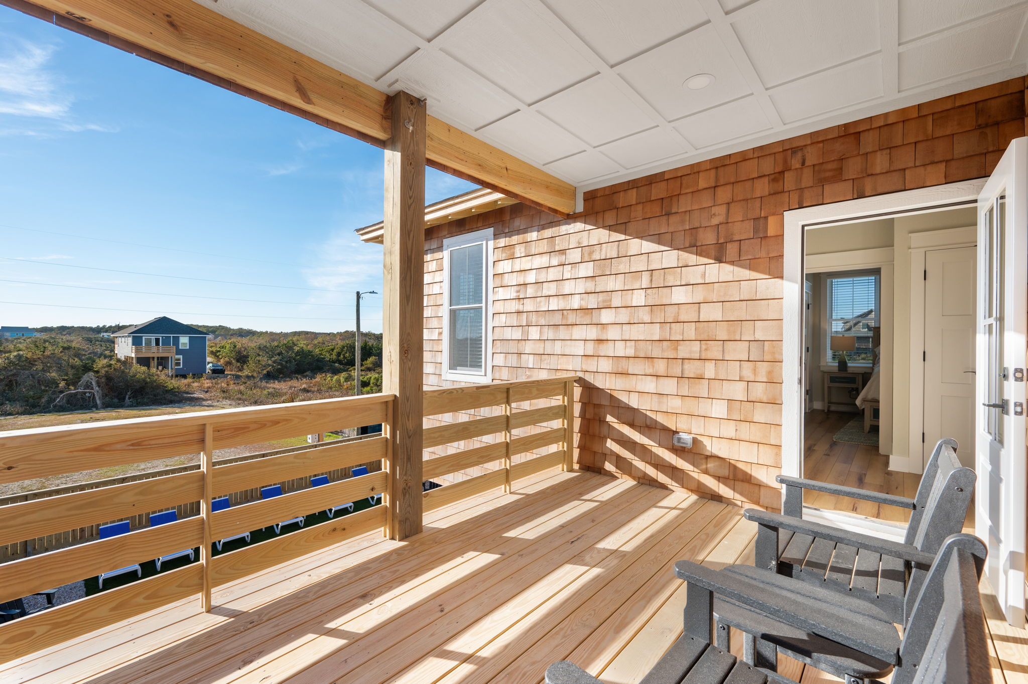 Een houten terras met uitzicht op een huis en het landschap.