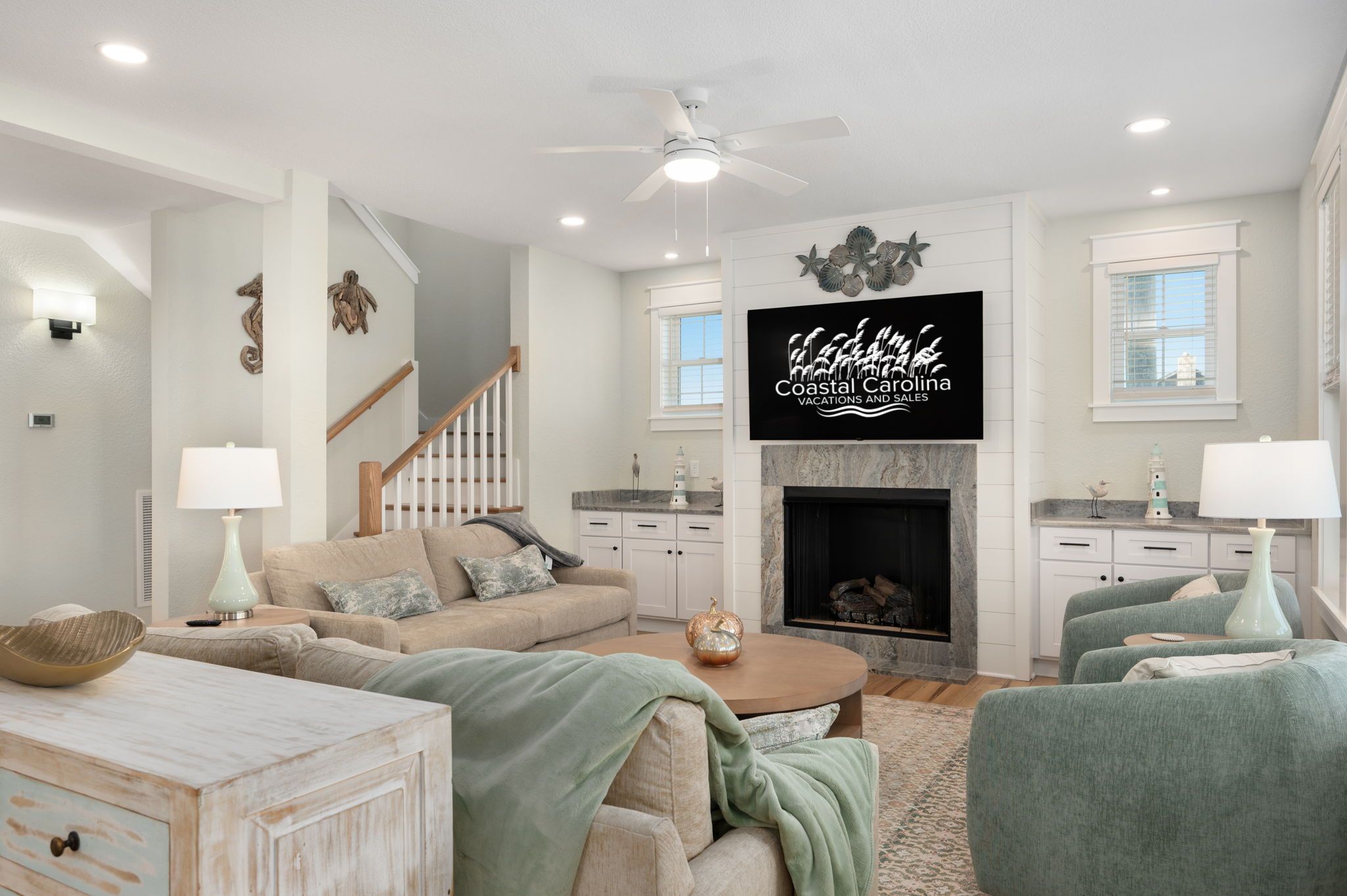 A spacious living room with a fireplace, a television mounted on the wall, and a staircase leading to another level.