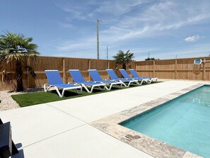 Une piscine avec des chaises longues bleues et une clôture en bois.