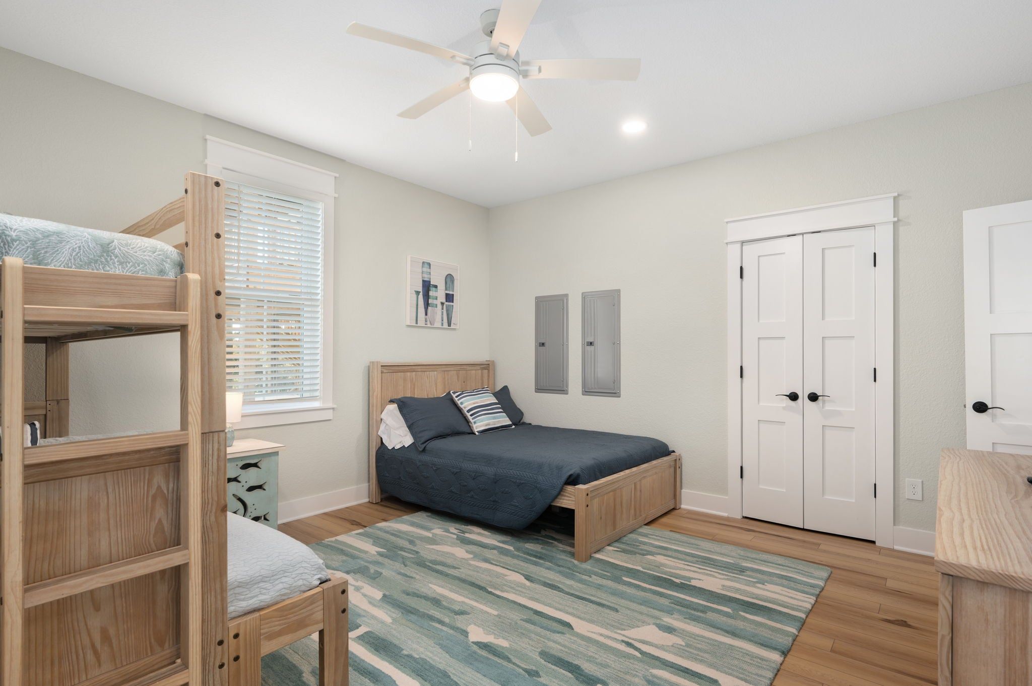 A bedroom with bunk beds, a single bed, a ceiling fan, and a door.