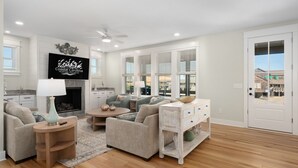 A spacious living room with a fireplace, comfortable seating, and a television. - Nags Head 369: New Construction, Private Pool, Hot Tub, Ocean Views! (Nags Head)