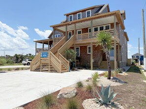 Un bâtiment à deux étages doté d’une terrasse en bois et d’un escalier menant à l’étage supérieur.