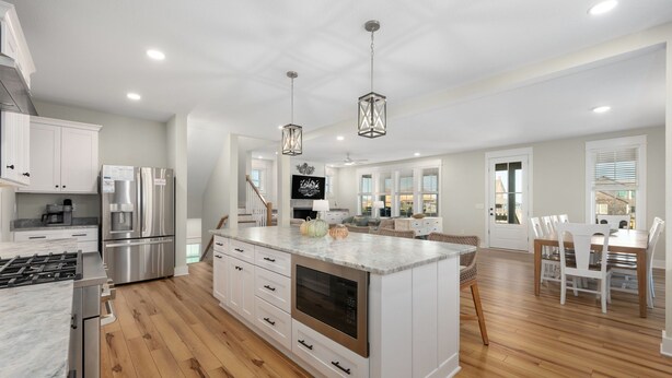 A spacious kitchen with modern appliances, a large island, and a dining area with white chairs. - Nags Head 369: New Construction, Private Pool, Hot Tub, Ocean Views! (Nags Head)