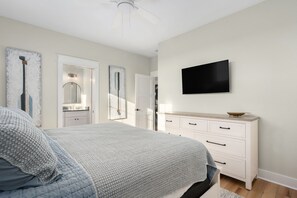 Un dormitorio con cama, cómoda, televisor y espejo.