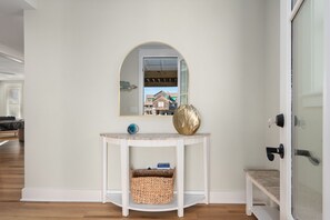 A white console table with a mirror, a decorative bowl, and a wicker basket.