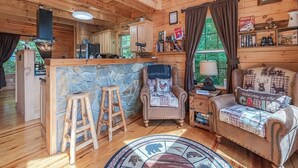 A cabin interior with a wooden interior, a stone accent wall, a bar area, and a cozy seating area with a fireplace.
