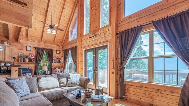 A cozy log cabin interior with a large sofa, a coffee table, and a bookshelf.