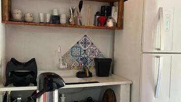Cozinha com geladeira, prateleiras com louças, chaleira e painel de backsplash estampado.