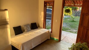 A bedroom with a bed, a refrigerator, and a view of the outside. - Hospedaria Labelle - Xandó Caraíva (Porto Seguro)