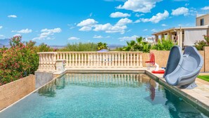 A swimming pool with clear water, a stone balustrade, and a view of mountains in the background. - Heated Pool, Waterslide, Mountain Views 3 Bedroom 2 Bathroom Tuscan Home (Fountain Hills)