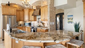 A spacious kitchen with granite countertops, wooden cabinets, and a large island with seating. - Heated Pool, Waterslide, Mountain Views 3 Bedroom 2 Bathroom Tuscan Home (Fountain Hills)