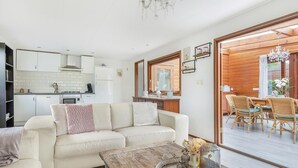 Una sala moderna con sofá, mesa de centro y comedor con sillas de mimbre.