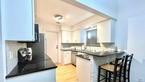 A modern kitchen with a black countertop, white cabinets, and a small island with bar stools.