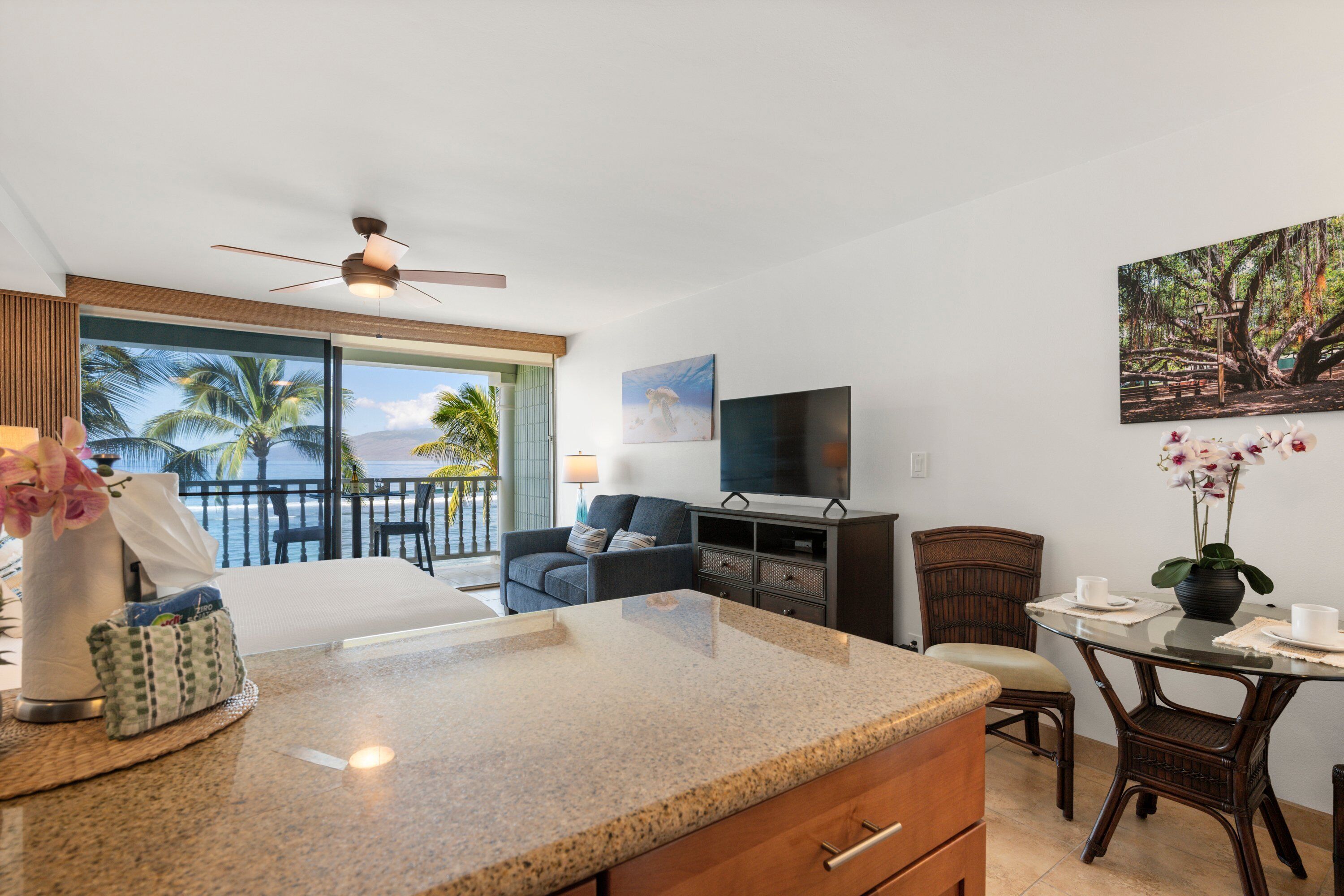 A hotel room with a balcony, a TV, a dining table, and a seating area.