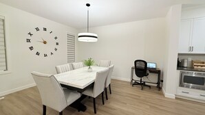 Et moderne køkken med hvide skabe, en indbygget ovn og et spiseområde med et marmorbord og stole.