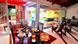 A dining area with a table set for two, featuring plates, cutlery, and a bottle of water. - Casa Santa María Búzios (Búzios)