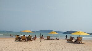 A beach with several yellow umbrellas and beach chairs. - Casa Santa María Búzios (Búzios)