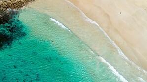 An aerial view of a beach with clear turquoise waters and a sandy shore. - Four Tallwood - Ocean Views (Narrawallee)