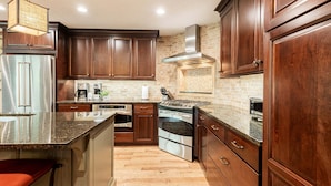 A kitchen with wooden cabinets, a stainless steel refrigerator, an oven, and a microwave.