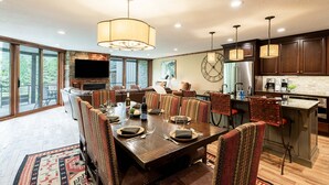 A spacious dining area with a large wooden table, multiple chairs, and a central chandelier.