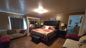 A bedroom with a large bed, a sofa, a chair, and a small table.