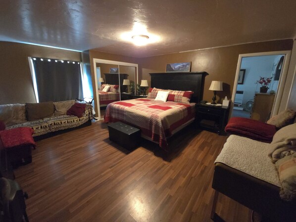 A bedroom with a large bed, a sofa, a chair, and a small table.