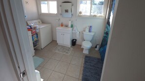 A compact bathroom with a washing machine, a sink, a toilet, and a window.