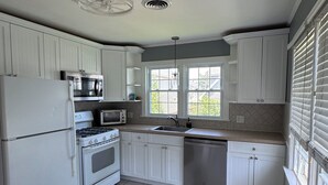A kitchen with white cabinets, a stove, a microwave, and a dishwasher. - Peaceful 2-bedroom apartment with AC in Spring Lake Heights close to the beach. (Spring Lake)