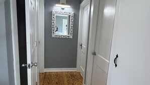 A hallway with wooden flooring, white doors, and a mirror on the wall. - Peaceful 2-bedroom apartment with AC in Spring Lake Heights close to the beach. (Spring Lake)