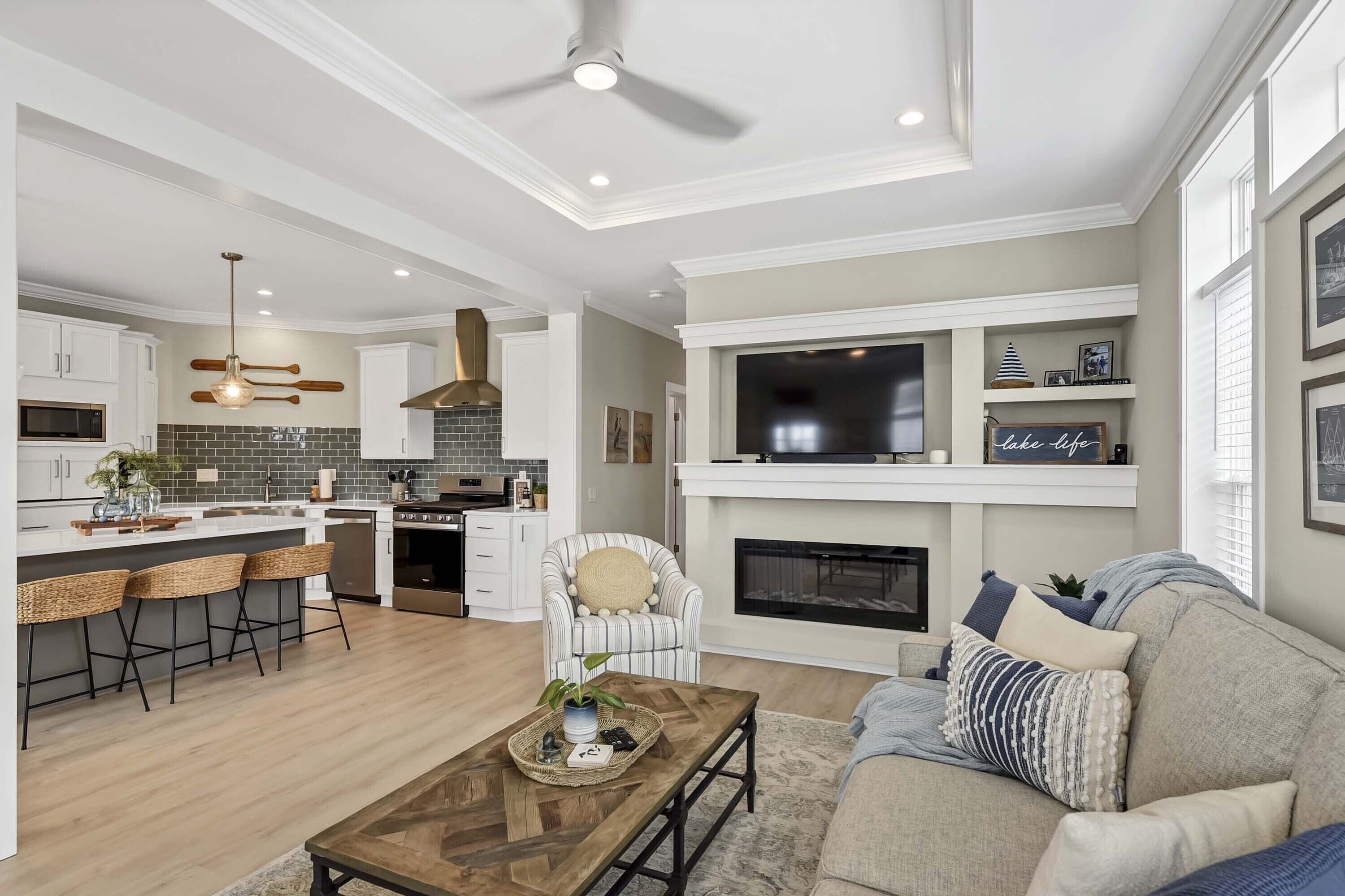 A modern kitchen with a central island, bar stools, and a dining area.