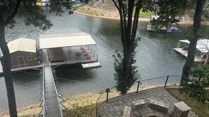 Een steiger aan de rivier met een overdekte zitplaats en een vuurkuil.