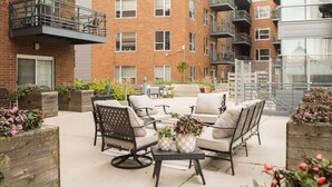An outdoor seating area with wicker furniture and planters with flowers. - Upscale Apartment Near Lake Michigan · Sleeps 6-7 (Milwaukee)