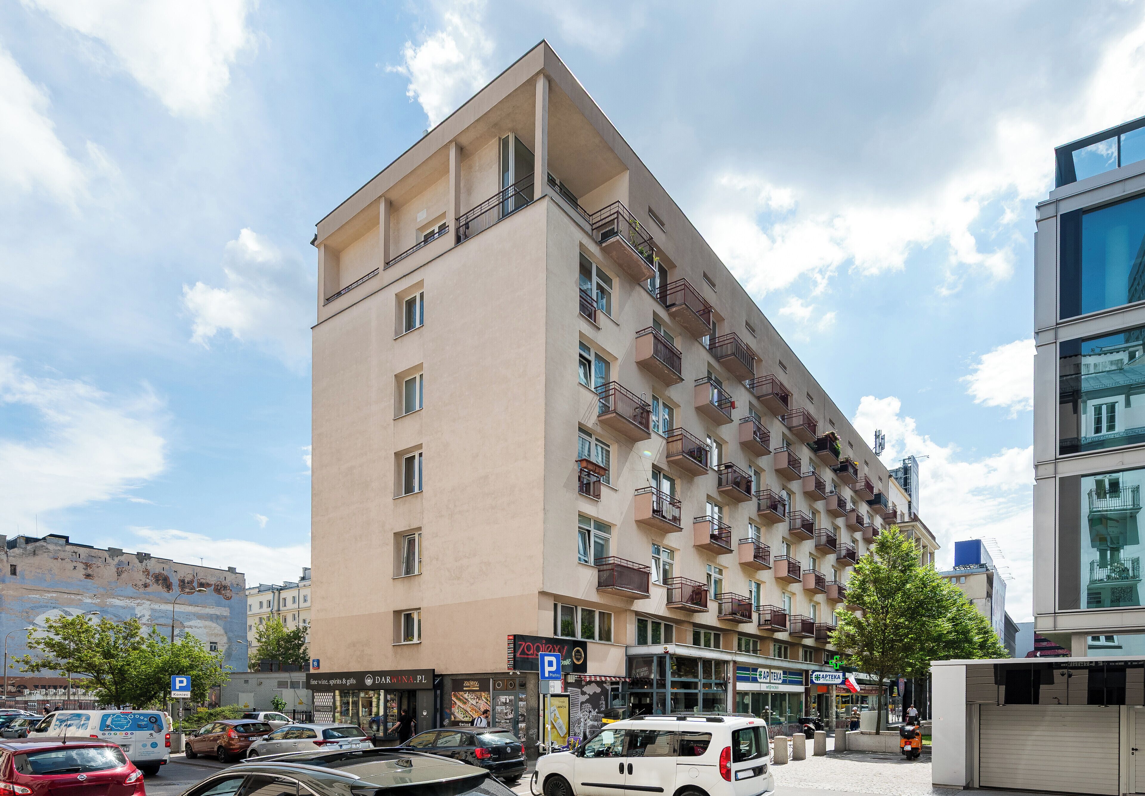 Ein mehrstöckiges Hotel mit Balkonen, einem Parkschild und verschiedenen Geschäften.