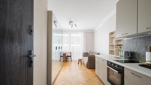 A modern kitchen with a herringbone floor, a built-in oven, and a dining area with a table and chairs.